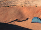 Shadow of Person Shaking Out Sleeping Bag by Tent