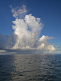 Small Rainbow Shines over Storm Clouds Above the Ocean