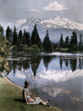 Buy Girl Sits by a Lake with Snow-Capped Mountains in the Background at AllPosters.com