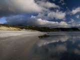 Sunlight Pierces Storm Clouds Illuminating an Empty and Remote Beach