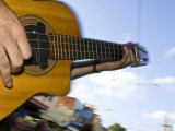 Musician's Fingers Strum the Cords of a Guitar During a Public Show