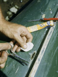 Man Mends a Hole in a Canvas Canoe with a Patch and Cement