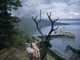 Buy Women Sit on Statue of Stag Overlooking Passing Train and Tour Boat at AllPosters.com