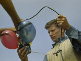 Buy Man Holds Electrical Leads to Equipment Tied to Flotation Balloons at AllPosters.com