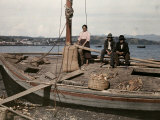 Woman and Two Men Sit on a Boat Used to Move Goods to Chiloe