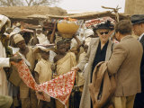 American Traveler Looks at Cloth in an Open-Air Market