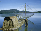 Buy Fisherman Stands in Canoe Beside Raft with Hut and Fishing Net at AllPosters.com