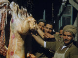 Buy Smiling Butcher Holds Up a Carcass of a Big-Tailed Sheep at AllPosters.com