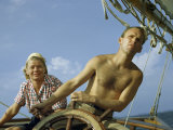 Man Steers a Sailboat as His Wife Helps to Navigate