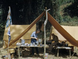 Buy Archeologist Writes While His Wife Cooks Dinner in a Camp Tent at AllPosters.com