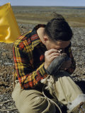 Scientist Inspects Rock Particles Attached to a Large Magnet
