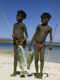 Smiling Boys Stand on Beach with Fish They Caught with Spears