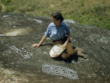 Buy Woman Inspects Ancient Petroglyphs Carved into Volcanic Rock at AllPosters.com