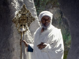 Old Ethiopian Orthodox Priest Holds a Large Brass Coptic Cross at Rock-Hewn Church of Adadi Maryam
