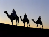 Three Camel Riders Silhouetted Against an Evening Sky