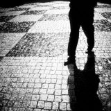 Silhouette of Mans Legs Walking on Cobblestone Street at Night