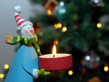 Buy Close-Up of a Snow Man Candle in Front of a Tree with Christmas Lights at AllPosters.com