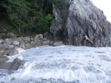 Young Woman Climbs on Cliff Boulders by the Sea