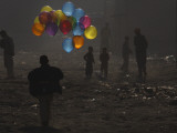 Afghan Boy Runs with Balloons to Join His Friends in Dusty Alley in Kabul, Afghanistan