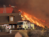 US Forest Service Air Tanker Drops Fire Retardant as the Fire Burns in the Hills Above a Home