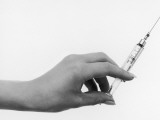 A Nurse Holds Up a Syringe, Ready to Perform an Injection on Her Patient - Ouch!