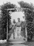 Couple Walking on Footpath Towards Rose Covered Pergola