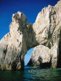 Sea kayaker paddles toward arch of rock, Cabo San Lucas, Baja