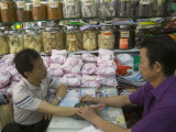 China, Hong Kong, Chinese Medicine Doctor Feeling Patient's Pulse at the Market