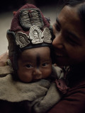 A Baby Wears a Protective Woolen Cap Adorned with Amulets and Needles