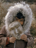 A Nunamiut Boy in a Fur-Trimmed Parka Holds a Mask of Caribou Hide