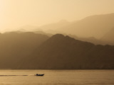 Speedboat Motoring Beneath Silhouetted Mountain Ridges Sloping Towards the Gulf of Oman