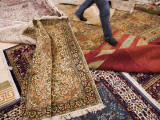 Salesman Walks on Carpets for Sale at Carpet Factory