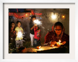 A Woman Lights Earthen Lamps as Children Ignite Firecrackers in New Delhi