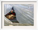 An Elderly Kosovar Woman Sits Behind a Plastic Wind Guard Around Her Spot