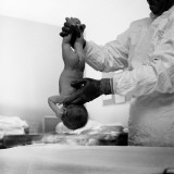 Doctor Holding Newborn Baby Upside-Down By Its Ankles