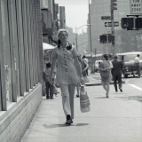 Woman in Polyester Pantsuit Walking Down City Street With Shopping Bag in Hand