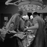 Surgical Team of Five Huddled Together, Operating on Patient