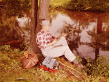 Man Sitting on Bank of Lake, Fishing
