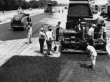 Road Construction Workers Using Machine To Lay New Asphalt on Road