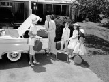Family Packing Suitcases in Trunk of Car Parked on Driveway, Preparing For Vacation
