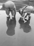 Two Kids Bending Over Playing in Mud Puddle