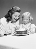 Mother and Daughter Looking at Birthday Cake With Three Candles on It, Smiling