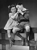 Boy and Girl Sitting on Fence Sharing Apple