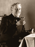 Mature Man Sitting at Table With Drink and Pipe, Raising Glass
