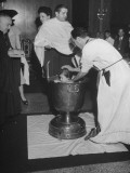 Small Child Being Christened in Water from Jordan River in a Large Metal Urn