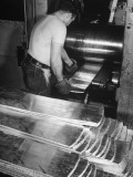 A Man Running Sheets of Silver Through a Compressor