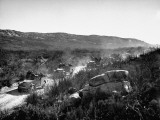 Soldiers in Vehicles with Weapons Traveling Along an Unpaved Road in a Rural Setting During WWII