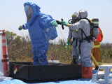 An Airman Stands in a Tub of Cleaning Solution During a Decontamination Process