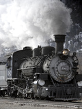 A Steam Train Puffing Smoke While Moving Down Tracks