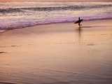 A Surfer Heads into the Waves Just as the Sun Is Setting
